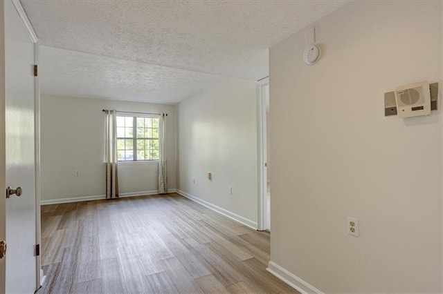 empty room with light hardwood / wood-style floors and a textured ceiling