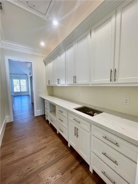 kitchen with light stone countertops, dark hardwood / wood-style flooring, crown molding, and white cabinetry