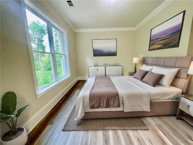 bedroom with ornamental molding and light hardwood / wood-style floors