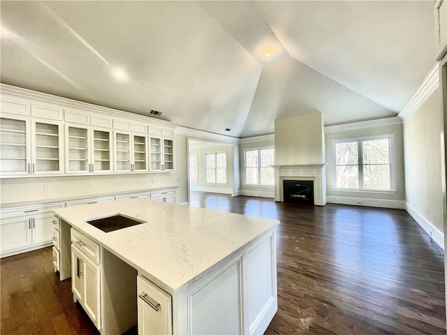 kitchen featuring light stone countertops, white cabinetry, a center island, and vaulted ceiling