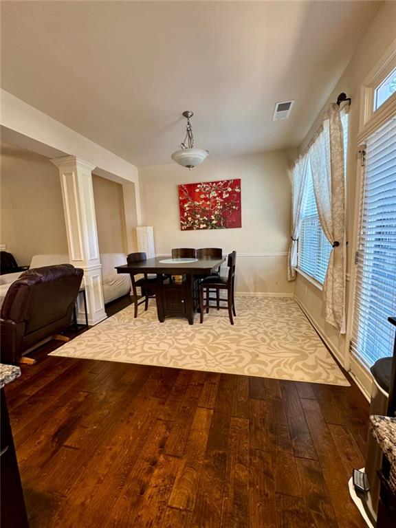 dining room with visible vents, hardwood / wood-style floors, and decorative columns