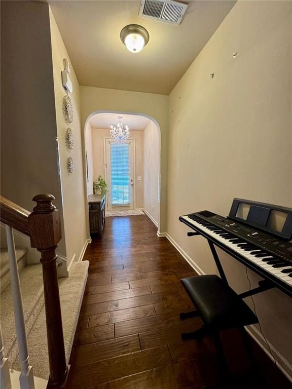 foyer entrance with baseboards, visible vents, arched walkways, stairway, and dark wood-style flooring