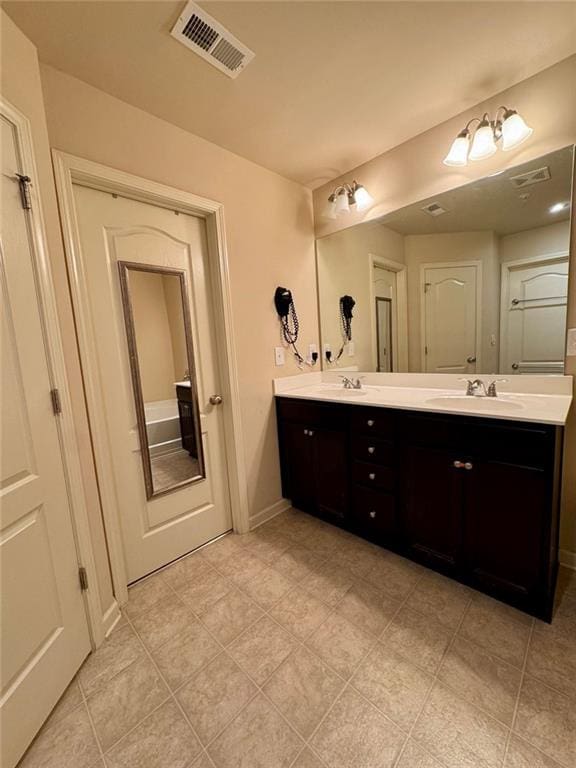 bathroom featuring double vanity, a sink, visible vents, and baseboards