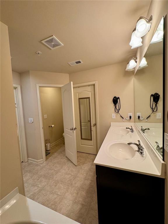 bathroom featuring visible vents, a sink, and double vanity