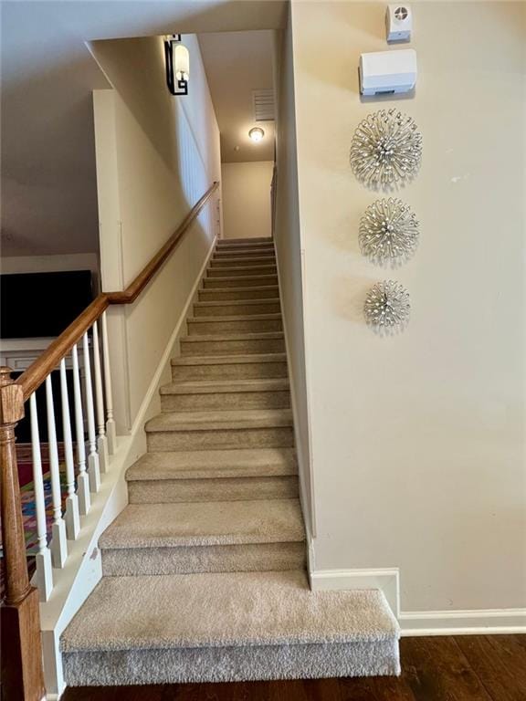 staircase featuring visible vents, baseboards, and wood finished floors