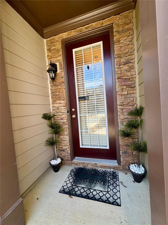 doorway to property featuring stone siding and a porch