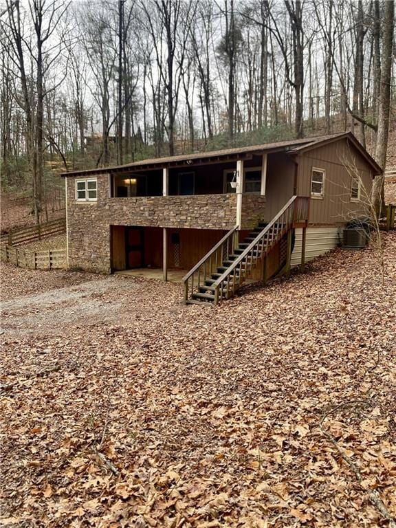 view of front of property with driveway, stairway, and stone siding