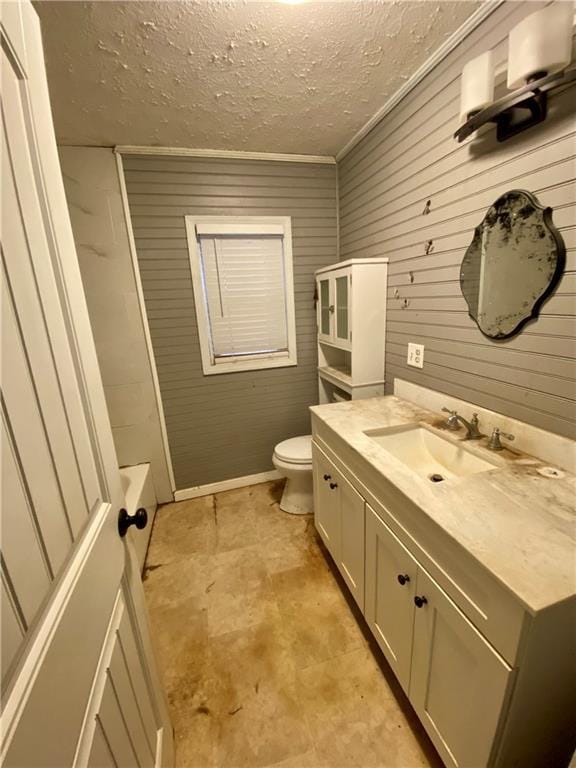 bathroom featuring toilet, a bathing tub, a textured ceiling, and vanity