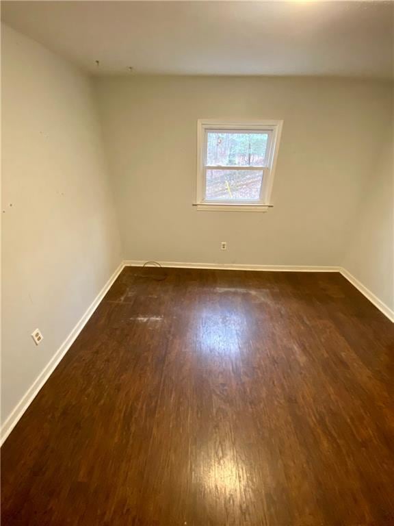 empty room with dark wood-style flooring and baseboards