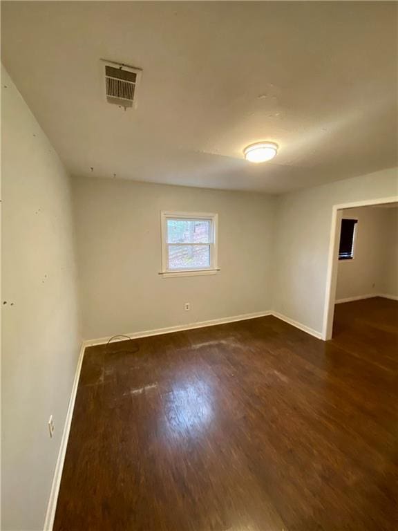 spare room featuring baseboards, visible vents, and dark wood-style flooring