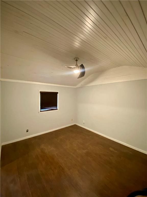 unfurnished room with ceiling fan, dark wood-type flooring, baseboards, vaulted ceiling, and crown molding