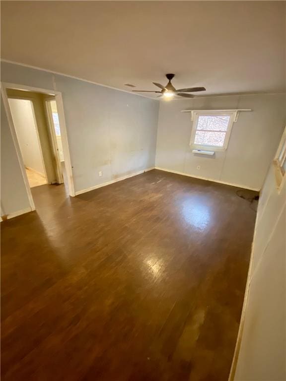 spare room with baseboards, a ceiling fan, and dark wood-type flooring