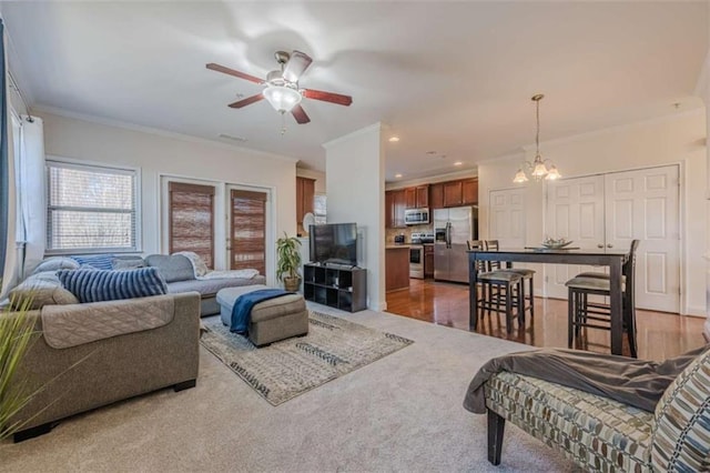 living room featuring ornamental molding, ceiling fan with notable chandelier, and hardwood / wood-style floors