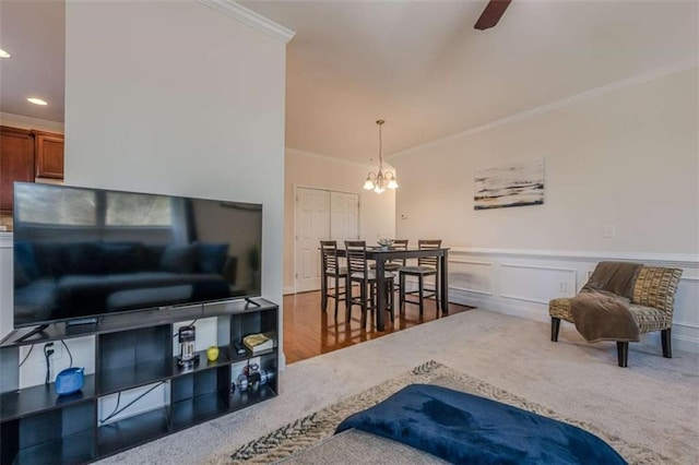 living room featuring crown molding, ceiling fan with notable chandelier, and carpet flooring