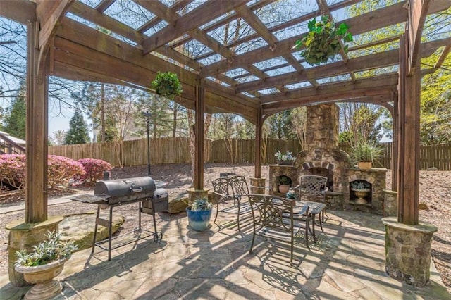 view of patio / terrace with area for grilling, a pergola, and an outdoor stone fireplace