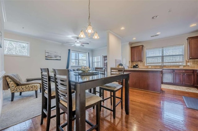 dining room featuring hardwood / wood-style flooring, crown molding, and ceiling fan