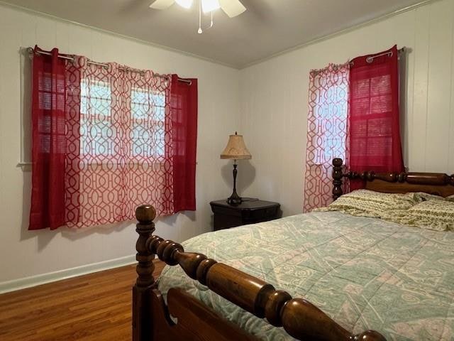 bedroom featuring ornamental molding, multiple windows, hardwood / wood-style floors, and ceiling fan