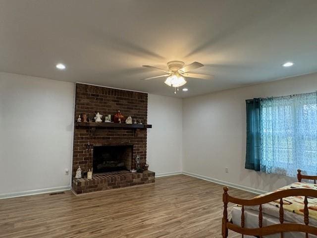 living room with a fireplace, hardwood / wood-style flooring, and ceiling fan