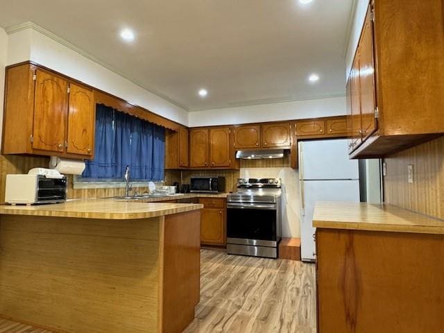 kitchen featuring sink, kitchen peninsula, appliances with stainless steel finishes, tasteful backsplash, and light hardwood / wood-style flooring