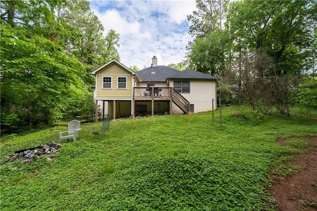 rear view of house with stairway, a wooden deck, a chimney, and a lawn