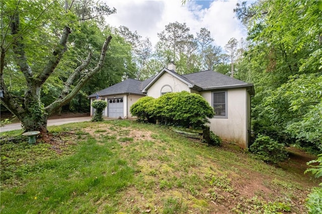 view of front of property featuring a garage, stucco siding, a chimney, and driveway