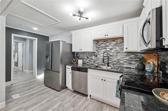 kitchen featuring appliances with stainless steel finishes, sink, dark stone countertops, and white cabinets