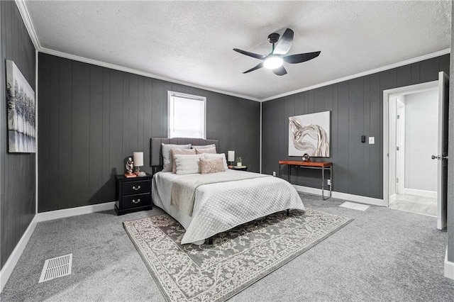 bedroom with wood walls, light colored carpet, ceiling fan, crown molding, and a textured ceiling