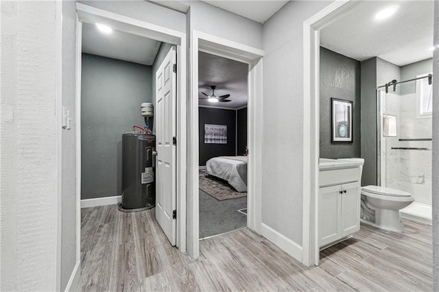 bathroom featuring ceiling fan, hardwood / wood-style floors, electric water heater, vanity, and a shower with shower door