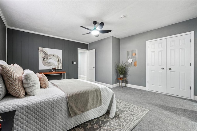 carpeted bedroom with wood walls, a textured ceiling, ornamental molding, a closet, and ceiling fan