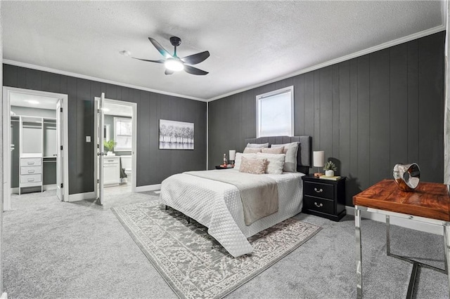 carpeted bedroom featuring ornamental molding, a walk in closet, a textured ceiling, and ceiling fan