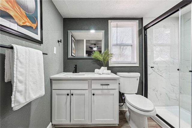 bathroom with a shower with door, vanity, wood-type flooring, a textured ceiling, and toilet