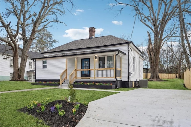 bungalow-style house featuring a front lawn, central air condition unit, and covered porch