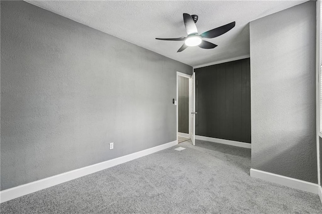 carpeted empty room with ceiling fan and a textured ceiling