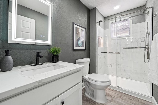 bathroom featuring walk in shower, toilet, a textured ceiling, vanity, and hardwood / wood-style flooring