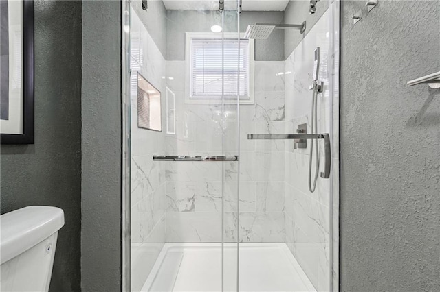 bathroom with a shower with door and toilet