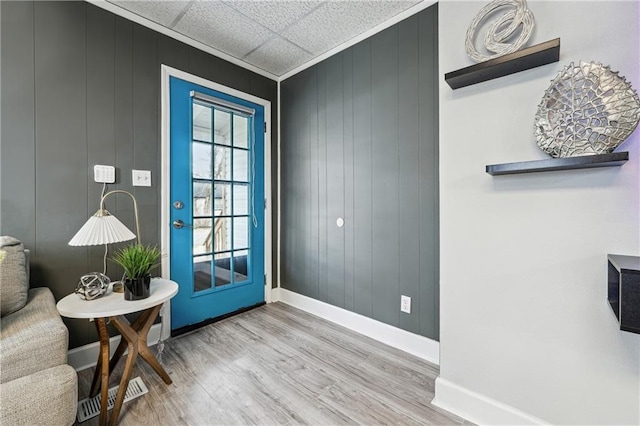 doorway with hardwood / wood-style flooring, ornamental molding, and wood walls