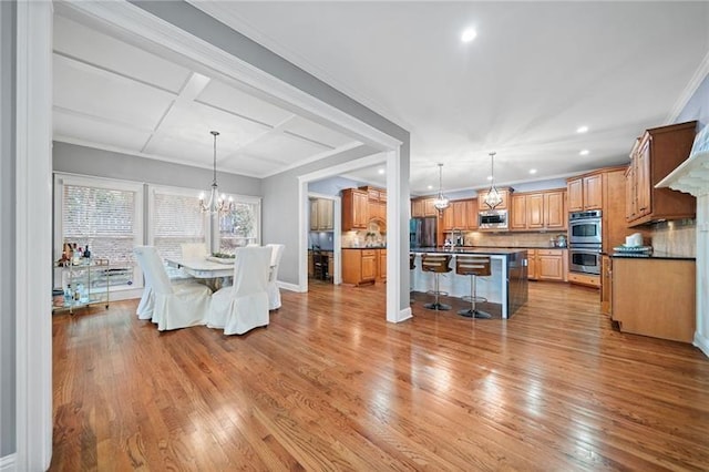 dining space featuring crown molding, coffered ceiling, a chandelier, and light wood-type flooring