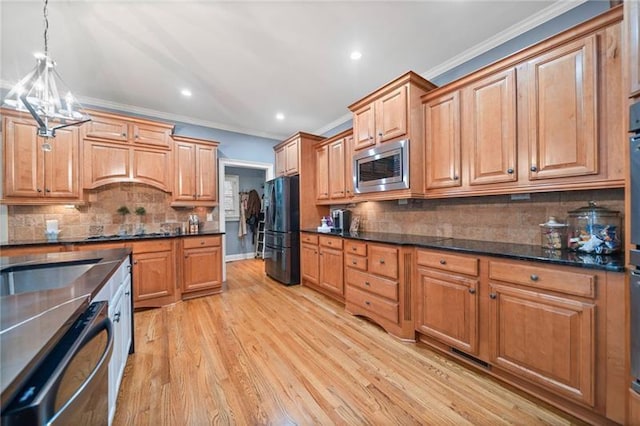 kitchen featuring crown molding, hanging light fixtures, stainless steel appliances, light hardwood / wood-style floors, and backsplash