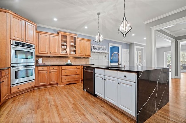 kitchen with decorative light fixtures, dishwasher, an island with sink, sink, and stainless steel double oven