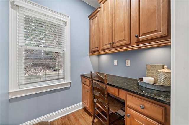 home office with light hardwood / wood-style flooring and built in desk