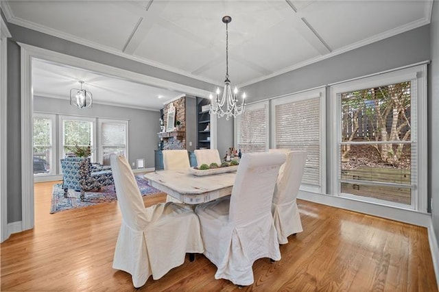 dining room featuring ornamental molding, coffered ceiling, a notable chandelier, and light wood-type flooring