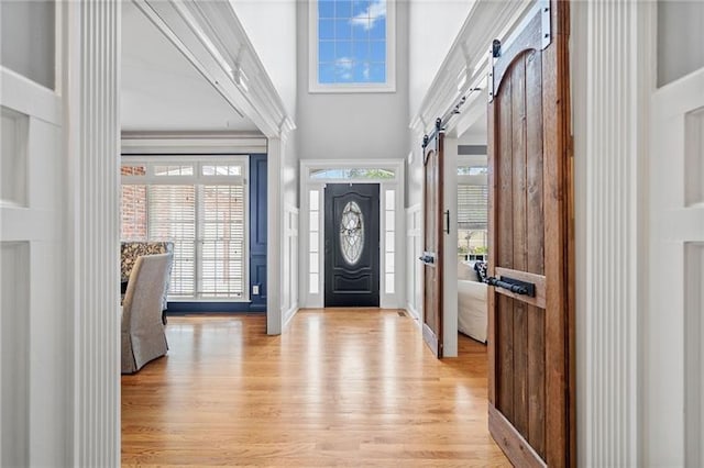 entryway with a barn door, a high ceiling, and light wood-type flooring