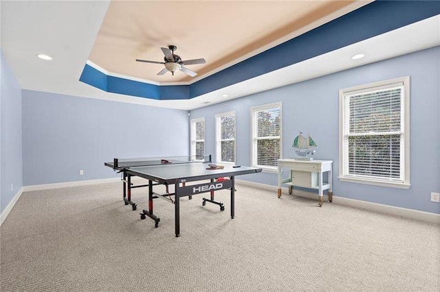 recreation room featuring ceiling fan, carpet flooring, a healthy amount of sunlight, and a tray ceiling