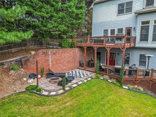 rear view of property with a wooden deck, a yard, a patio area, and a fire pit