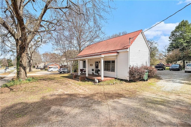 view of front of property featuring covered porch, driveway, and metal roof