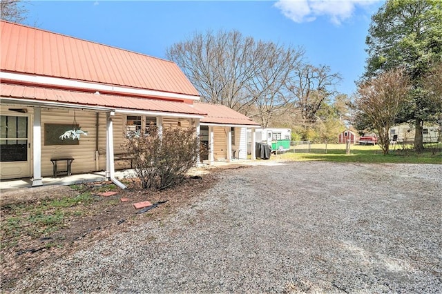 view of property exterior featuring metal roof and fence