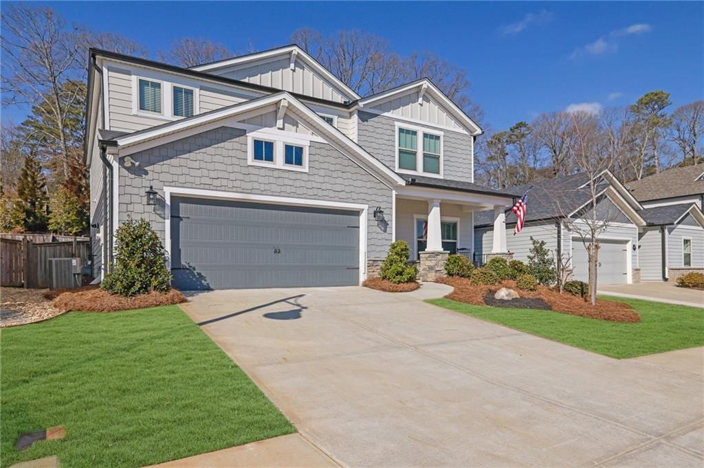 craftsman house featuring cooling unit, a garage, a front yard, and covered porch