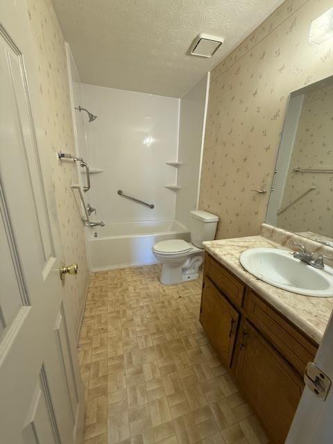 full bath with vanity, toilet, brick patterned floor, wallpapered walls, and shower / bath combination