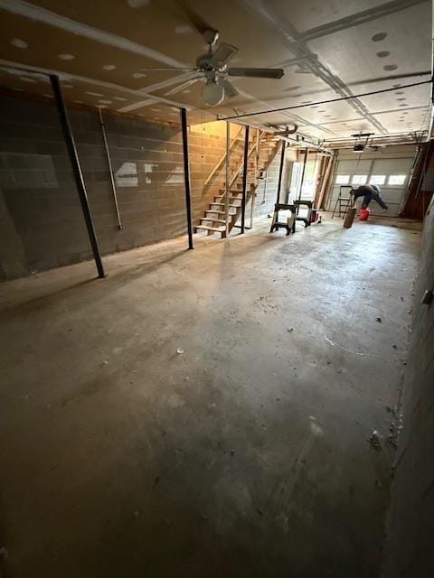 unfinished basement featuring concrete block wall and stairway