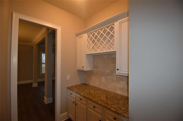 kitchen featuring backsplash, light stone countertops, dark hardwood / wood-style flooring, and white cabinetry